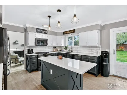 a kitchen with stainless steel appliances granite countertop a sink a stove a refrigerator cabinets and chairs