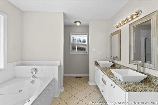 a spacious bathroom with a granite countertop tub sink and mirror