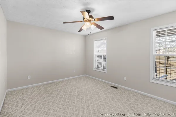 an empty room with windows and fan