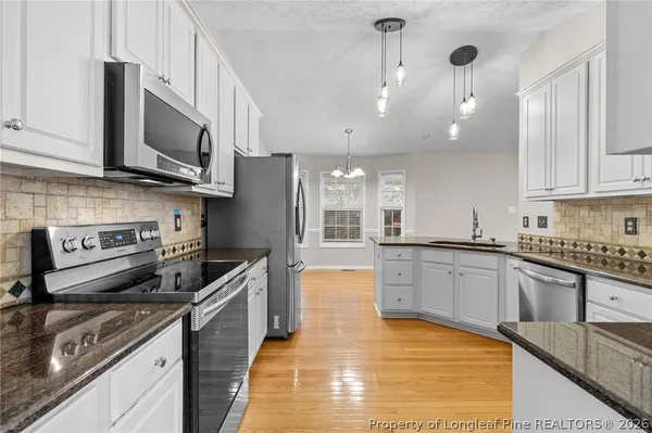 a kitchen with stainless steel appliances granite countertop a sink a stove and cabinets