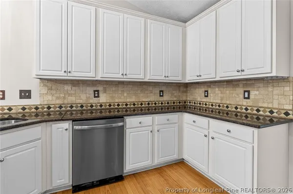 a kitchen with granite countertop a sink stainless steel appliances white cabinets and a window