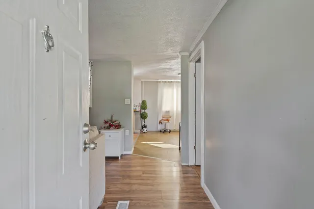 a view of a hallway with wooden floor and a living room