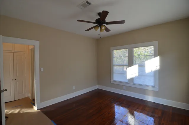 a view of empty room with wooden floor and fan