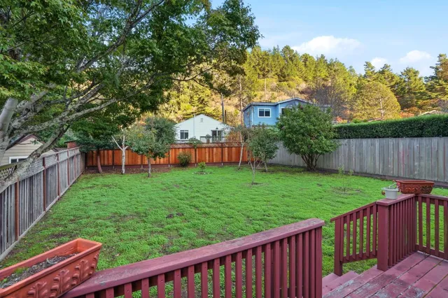 a view of a house with backyard and wooden fence