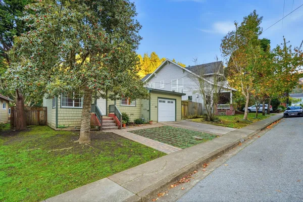 a view of a house with a yard and large tree