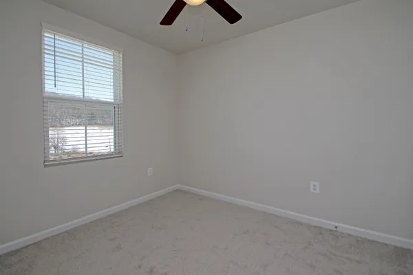 an empty room with a window and a fan
