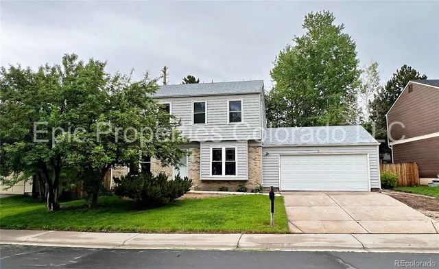 a front view of a house with a garden and trees