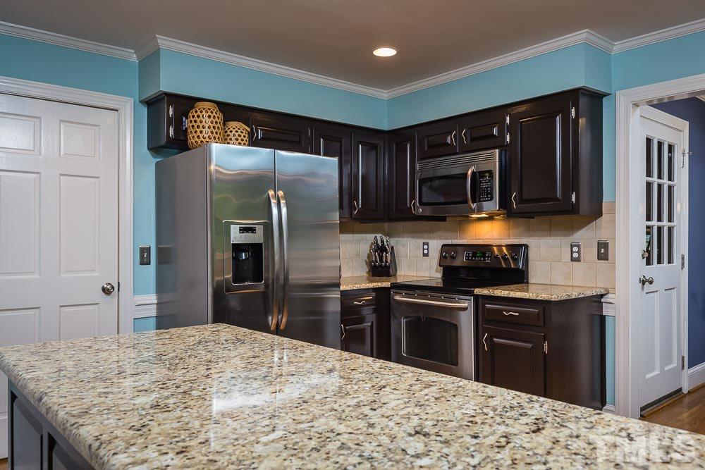 717 Bennington Drive Raleigh, NC 27615 - Photo 7 of 25 a kitchen with stainless steel appliances kitchen island granite countertop a refrigerator stove top oven and sink