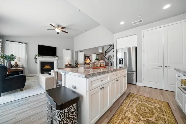 a kitchen with stainless steel appliances granite countertop a stove top oven a sink dishwasher a dining table and chairs with wooden floor