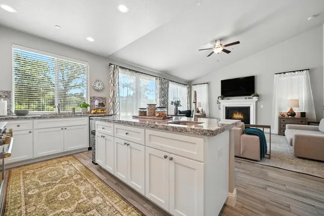 a kitchen with stainless steel appliances granite countertop a table chairs sink and cabinets