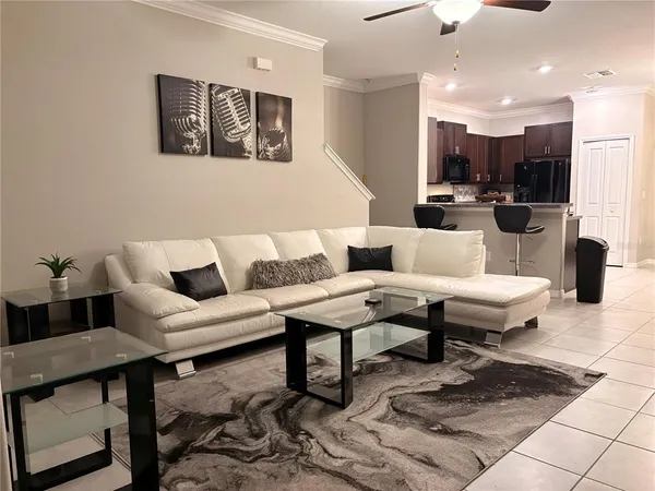 a living room with couches a table and kitchen view with wooden floor