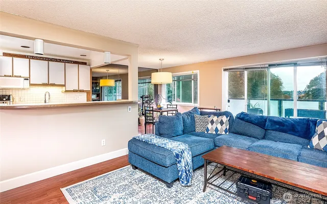 a kitchen with stainless steel appliances kitchen island granite countertop a table chairs and a wooden floor