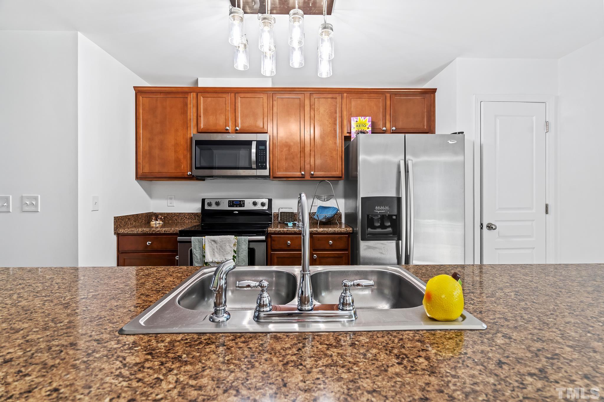 2931 Berkeley Springs Place Raleigh, NC 27616 - Photo 17 of 32 a kitchen with stainless steel appliances granite countertop a sink a stove a granite counter tops and a view of living room