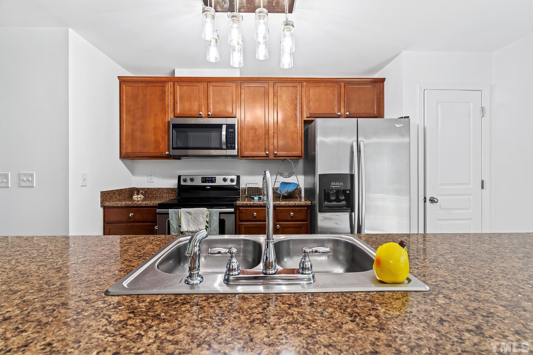 2931 Berkeley Springs Place Raleigh, NC 27616 - Photo 18 of 32 a kitchen with granite countertop a refrigerator a stove a microwave a sink and a counter top space