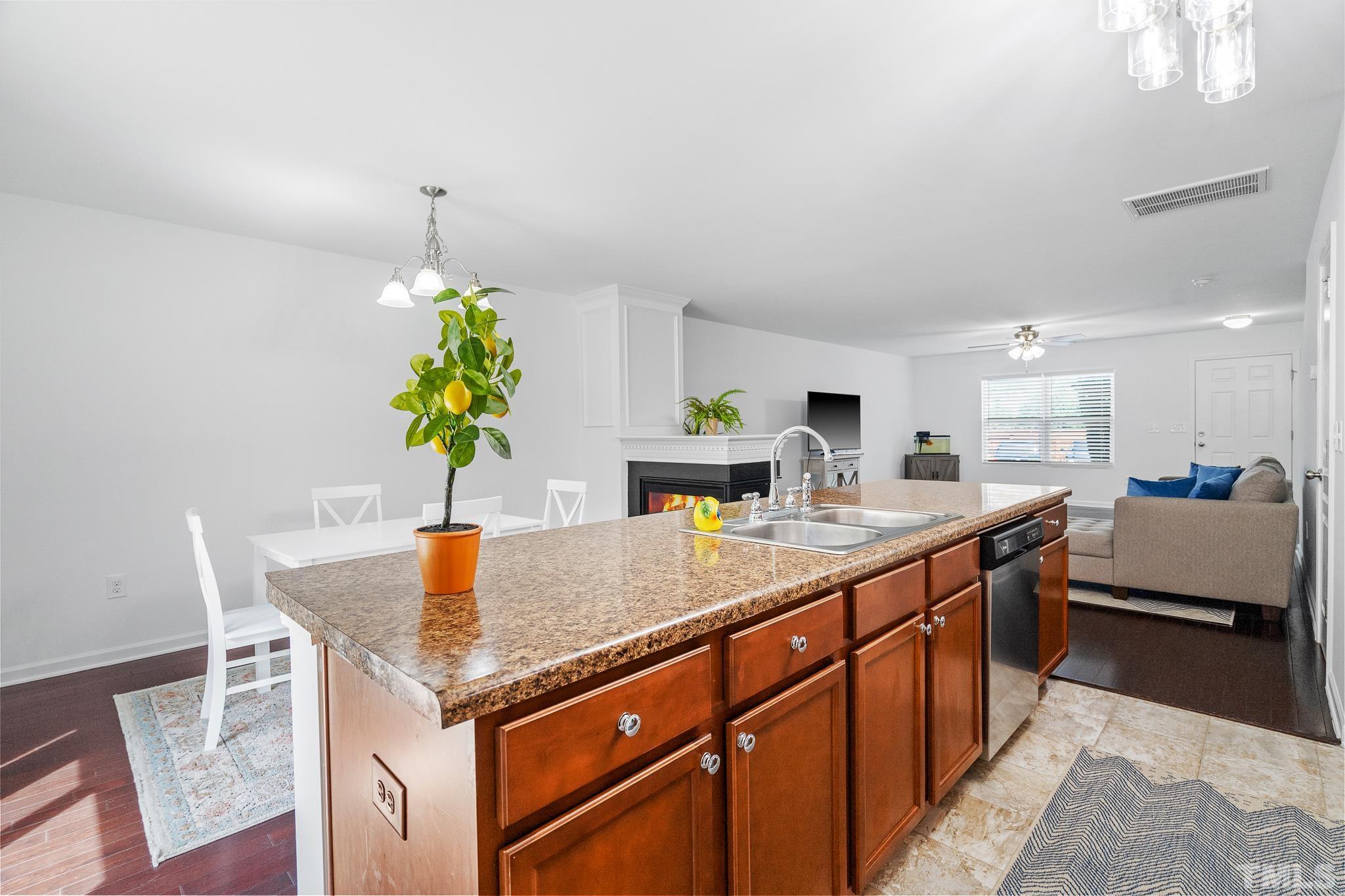 2931 Berkeley Springs Place Raleigh, NC 27616 - Photo 19 of 32 a kitchen with stainless steel appliances granite countertop sink stove and white cabinets with wooden floor