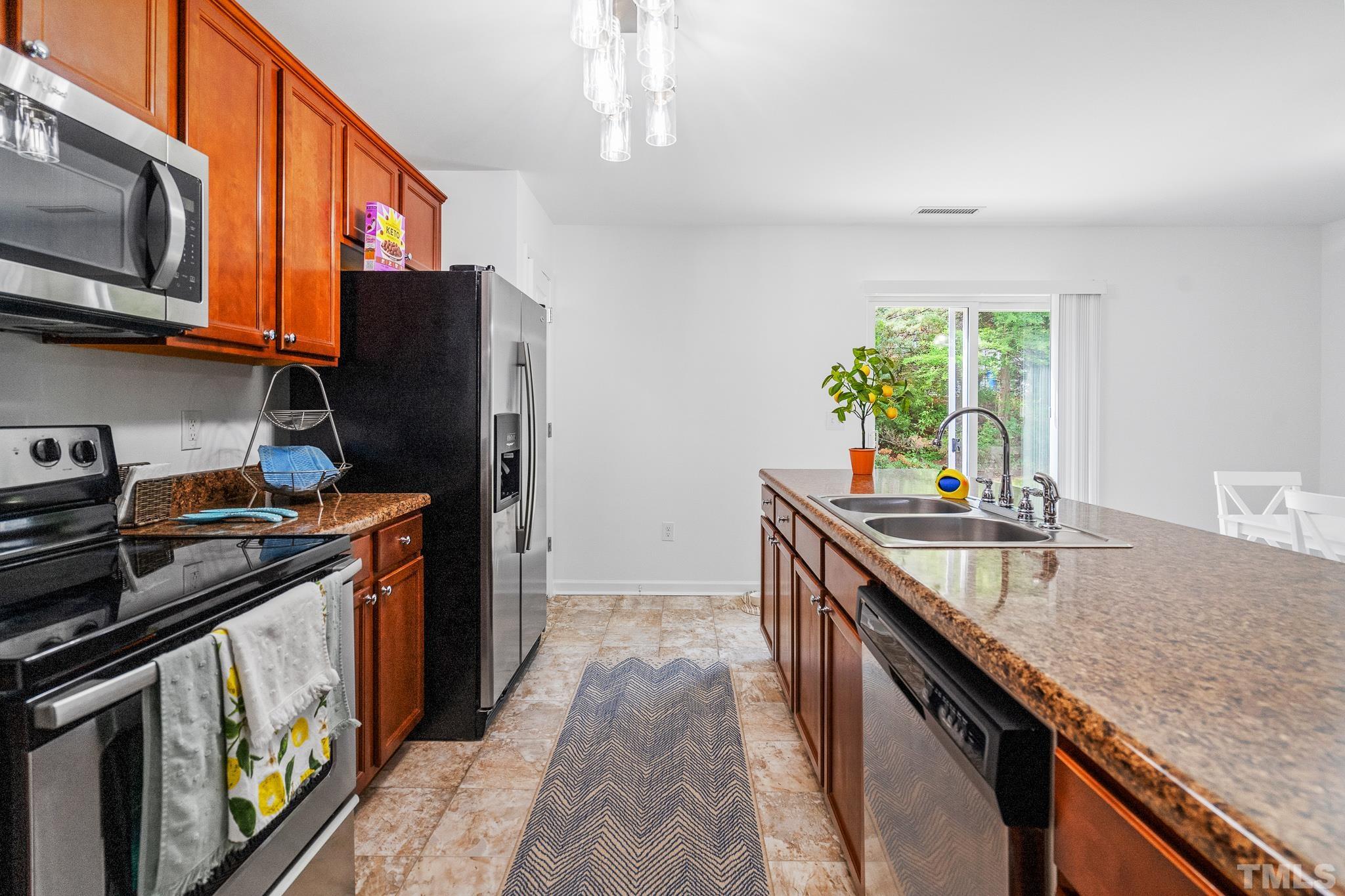2931 Berkeley Springs Place Raleigh, NC 27616 - Photo 21 of 32 a kitchen with stainless steel appliances granite countertop a sink a stove and a refrigerator