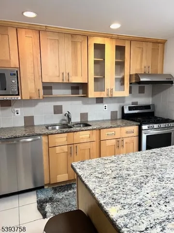 a kitchen with stainless steel appliances granite countertop a stove a sink dishwasher and a microwave oven with white cabinets