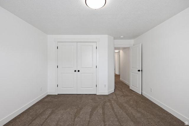 1139 South 4475 West West Point, UT 84015 - Photo 24 of 33 Unfurnished bedroom featuring dark carpet, a closet, and a textured ceiling