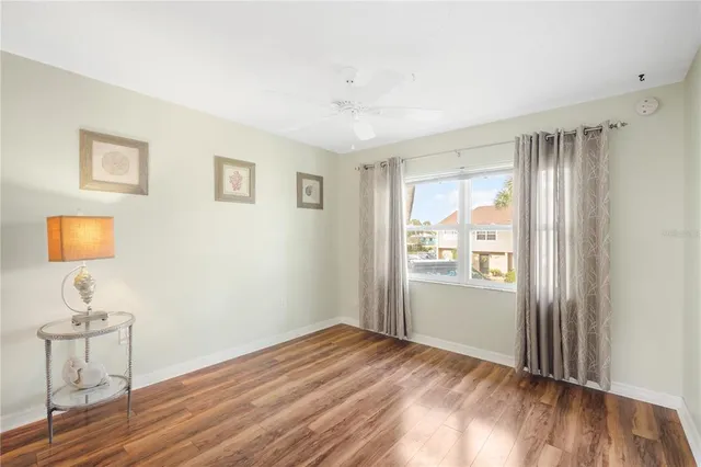 a view of empty room with wooden floor and fan