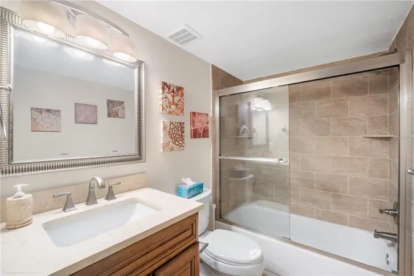 a bathroom with a bathtub shower sink vanity mirror and toilet