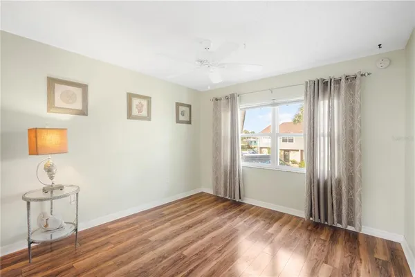 a view of empty room with wooden floor and fan