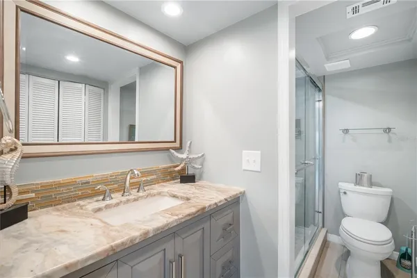 a bathroom with a granite countertop sink a toilet and a mirror