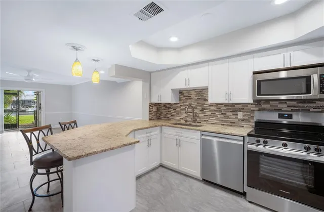 a kitchen with stainless steel appliances granite countertop a stove a sink and a microwave