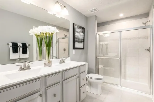 a bathroom with a double vanity sink toilet mirror and shower