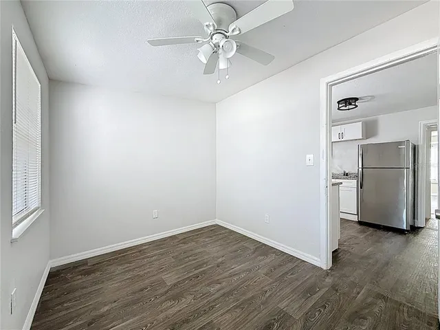 a view of a kitchen with a fridge a ceiling fan and wooden floor