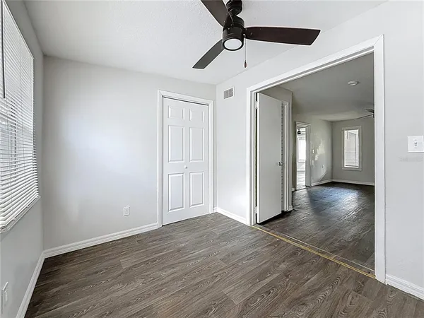 an empty room with wooden floor chandelier and windows