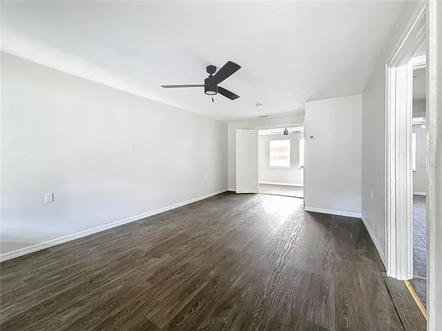 an empty room with wooden floor and ceiling fan