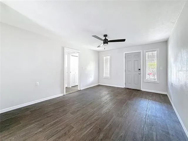 a view of empty room with wooden floor and ceiling fan