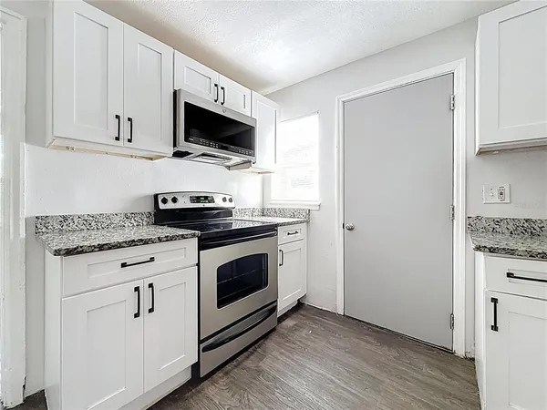 a kitchen with stainless steel appliances granite countertop a stove a microwave and a refrigerator