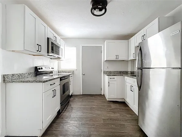 a kitchen with granite countertop white cabinets and white appliances