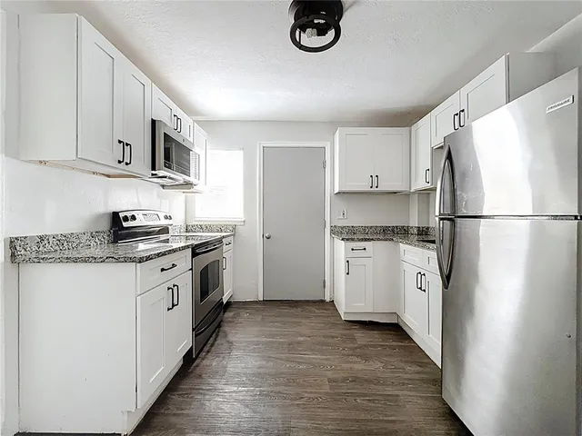 a kitchen with granite countertop white cabinets and white appliances