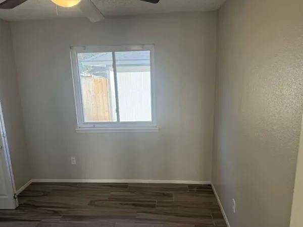 a view of an empty room with wooden floor and a window