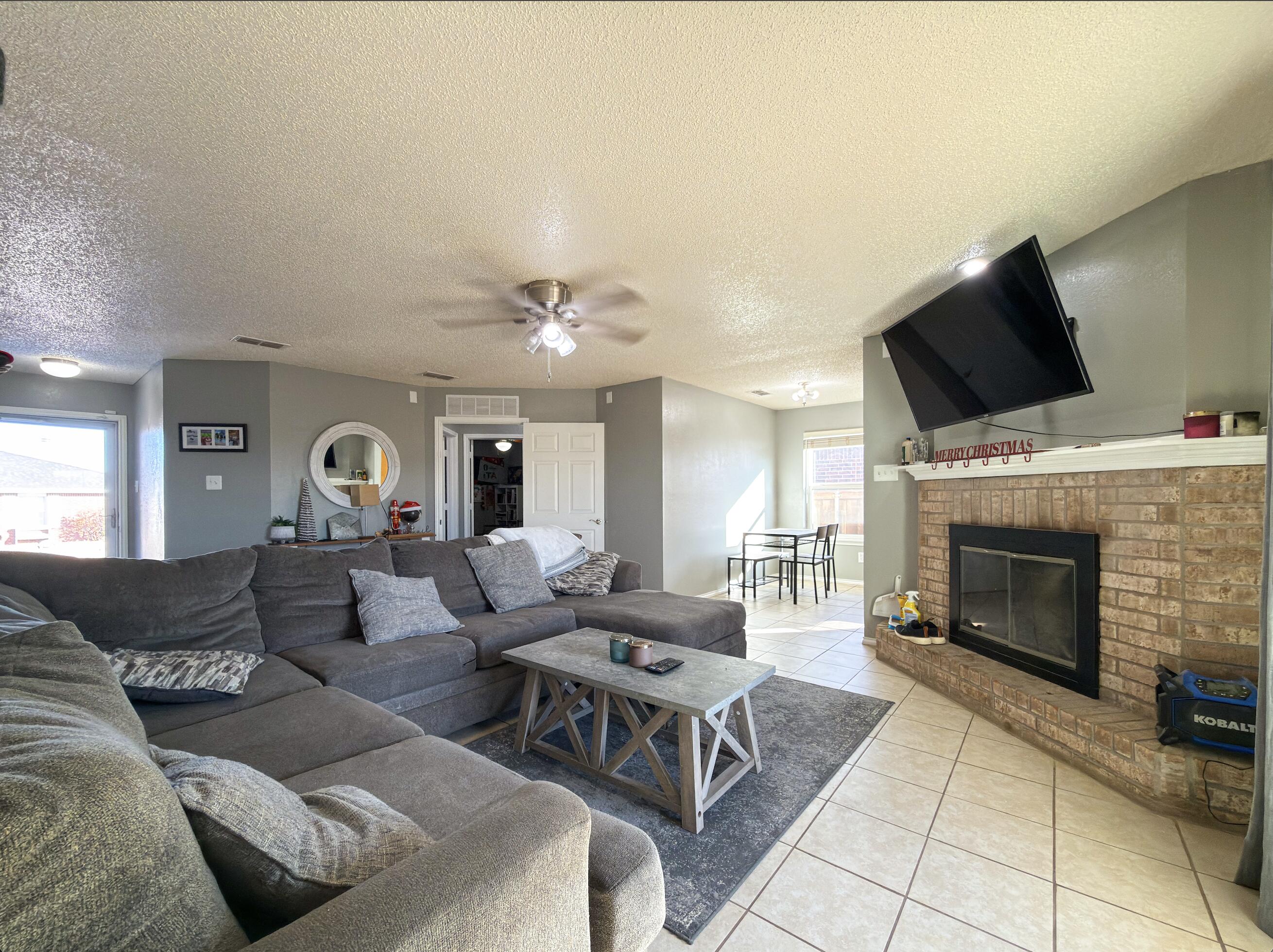 6123 39th Street Lubbock, TX 79407 - Photo 3 of 13 a living room with furniture a fireplace and a flat screen tv