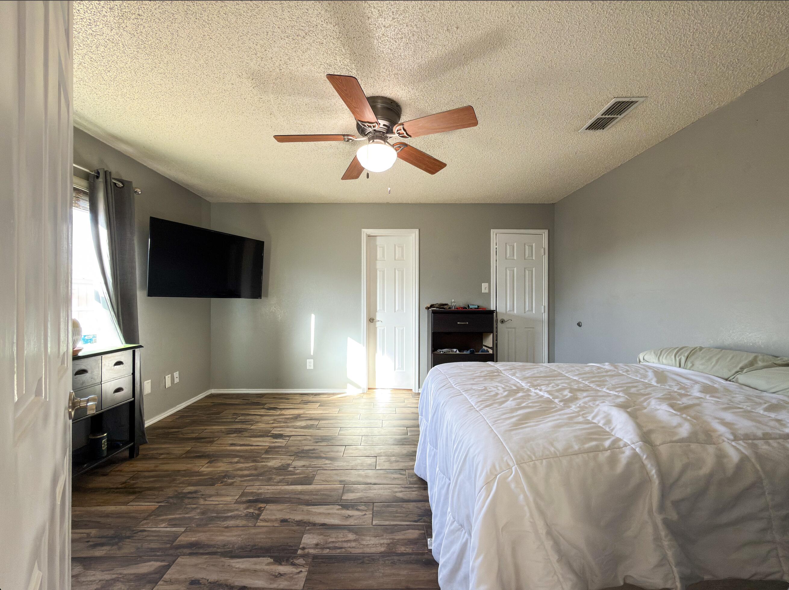 6123 39th Street Lubbock, TX 79407 - Photo 6 of 13 a spacious bedroom with a bed and a flat screen tv