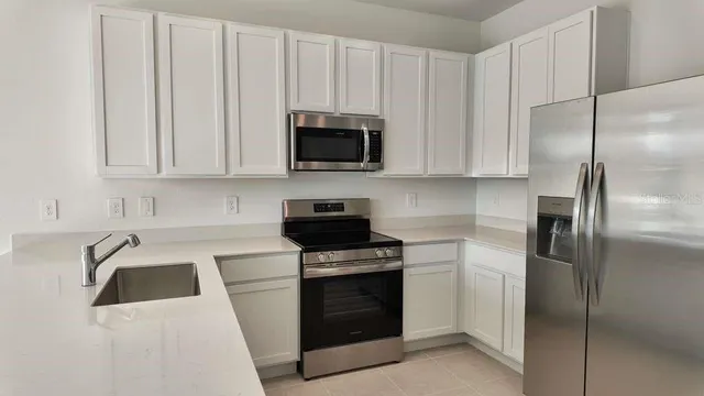 a kitchen with white cabinets and stainless steel appliances