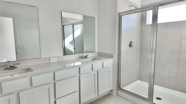 a bathroom with a double vanity sink mirror and shower