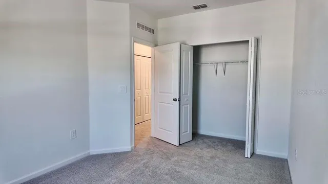 a view of an empty room with closet and a window