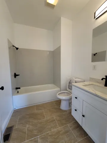 a bathroom with a granite countertop toilet a sink and bathtub