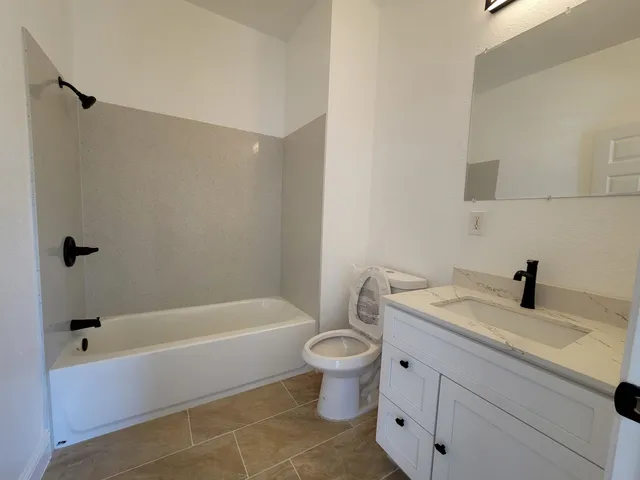 a bathroom with a granite countertop sink a toilet and bathtub