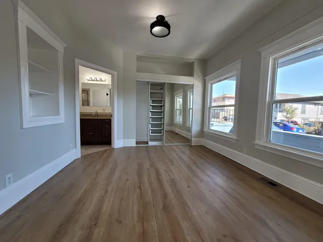 an empty room with wooden floor and windows