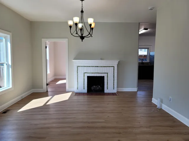 a view of a livingroom with a fireplace wooden floor and chandelier