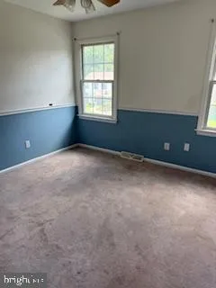 an empty room with windows and fan