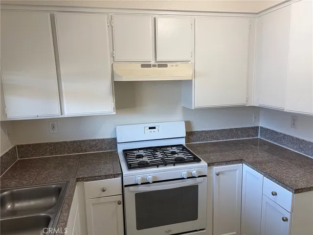 a kitchen with granite countertop a sink a stove and cabinets