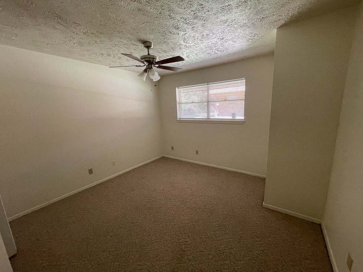 704 Cline Street Huntsville, TX 77340 - Photo 8 of 21 an empty room with a ceiling fan and carpet