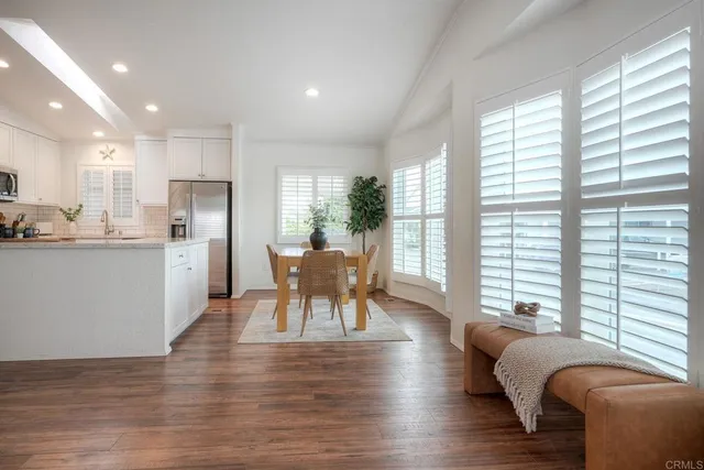 a kitchen with stainless steel appliances granite countertop a stove a refrigerator a kitchen island a dining table and chairs with wooden floor