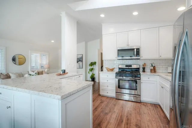 a kitchen with kitchen island granite countertop a sink cabinets and stainless steel appliances